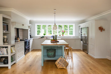 Example of a large transitional u-shaped medium tone wood floor and brown floor eat-in kitchen design in Hertfordshire with a double-bowl sink, shaker cabinets, white cabinets, quartz countertops, gray backsplash, stone slab backsplash, stainless steel appliances, an island and gray countertops