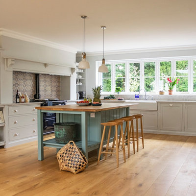 Inspiration for a large transitional u-shaped medium tone wood floor and brown floor eat-in kitchen remodel in Hertfordshire with a double-bowl sink, shaker cabinets, white cabinets, quartz countertops, gray backsplash, stone slab backsplash, stainless steel appliances, an island and gray countertops