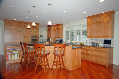 ポートランド(メイン)にある中くらいなおしゃれなキッチン (中間色木目調キャビネット、グレーのキッチンパネル、セメントタイルのキッチンパネル、パネルと同色の調理設備、無垢フローリング) の写真