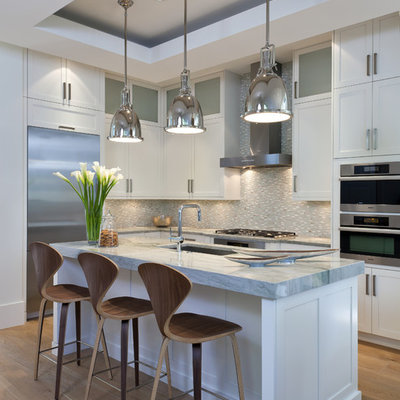 Kitchen - mid-sized transitional l-shaped medium tone wood floor kitchen idea in Miami with an undermount sink, shaker cabinets, white cabinets, gray backsplash, mosaic tile backsplash, stainless steel appliances and an island