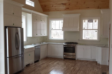 Inspiration for a large farmhouse u-shaped light wood floor and brown floor enclosed kitchen remodel in Atlanta with a farmhouse sink, white cabinets, stainless steel appliances, no island, shaker cabinets and granite countertops