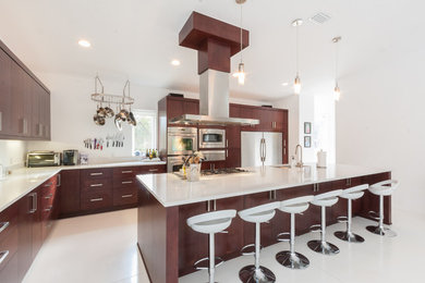 Example of a trendy l-shaped eat-in kitchen design in Jacksonville with an undermount sink, flat-panel cabinets, dark wood cabinets, quartz countertops, white backsplash and stainless steel appliances