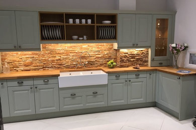 Inspiration for a country l-shaped kitchen in Surrey with a double-bowl sink, shaker cabinets, green cabinets, wood worktops, brown splashback and ceramic splashback.