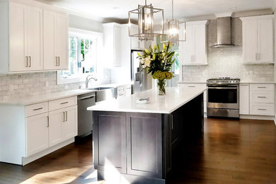 Example of a large trendy l-shaped medium tone wood floor and brown floor eat-in kitchen design in New York with a farmhouse sink, shaker cabinets, white cabinets, granite countertops, white backsplash, marble backsplash, stainless steel appliances and an island