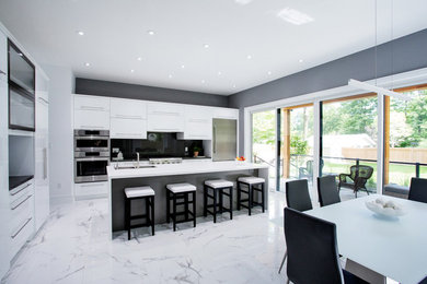 Example of a large minimalist l-shaped marble floor and white floor eat-in kitchen design in Toronto with an undermount sink, flat-panel cabinets, white cabinets, quartz countertops, black backsplash, stone slab backsplash, stainless steel appliances, an island and white countertops