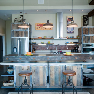 This is an example of a large industrial galley open plan kitchen in Other with a double-bowl sink, distressed cabinets, metallic splashback, stainless steel appliances, concrete floors and with island.