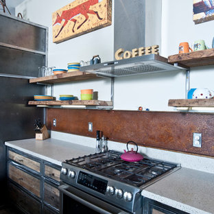 Photo of a large industrial galley open plan kitchen in Other with a double-bowl sink, distressed cabinets, recycled glass benchtops, metallic splashback, stainless steel appliances, concrete floors and with island.