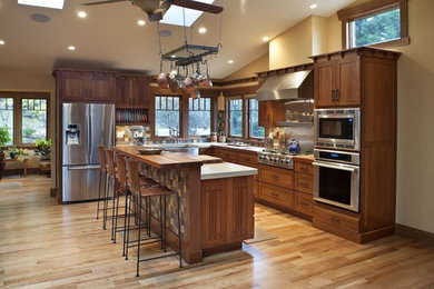 Inspiration for a craftsman light wood floor eat-in kitchen remodel in Other with a farmhouse sink, shaker cabinets, dark wood cabinets, quartz countertops, multicolored backsplash, porcelain backsplash, stainless steel appliances and an island