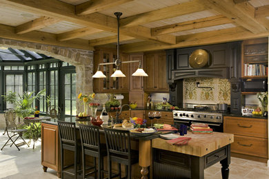 Large mountain style travertine floor and brown floor eat-in kitchen photo in Chicago with raised-panel cabinets, medium tone wood cabinets, multicolored backsplash, stainless steel appliances and an island