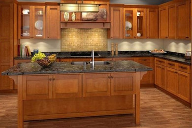 Example of a mid-sized arts and crafts l-shaped light wood floor enclosed kitchen design in Salt Lake City with a drop-in sink, shaker cabinets, light wood cabinets, onyx countertops, beige backsplash, stone tile backsplash, stainless steel appliances and an island