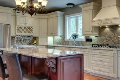 Example of a l-shaped medium tone wood floor kitchen pantry design in St Louis with a drop-in sink, raised-panel cabinets, white cabinets, granite countertops, gray backsplash, stone slab backsplash, stainless steel appliances and an island