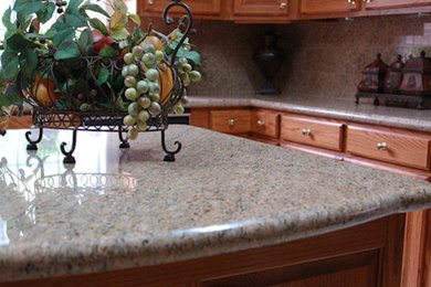 Example of a mid-sized l-shaped kitchen design in New Orleans with flat-panel cabinets, medium tone wood cabinets, granite countertops, beige backsplash, stone slab backsplash and an island