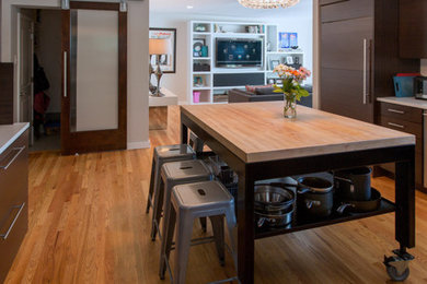 Cette photo montre une grande cuisine ouverte moderne en U avec un placard à porte plane, des portes de placard marrons, un électroménager en acier inoxydable, un sol en bois brun et îlot.