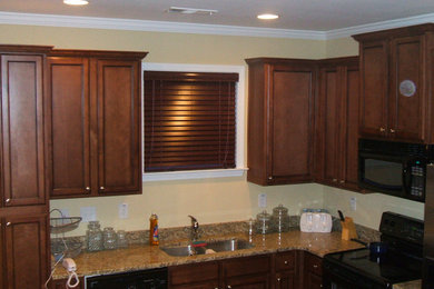 Kitchen photo in New Orleans with dark wood cabinets, beige backsplash and black appliances