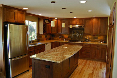 Inredning av ett avskilt, mellanstort l-kök, med en undermonterad diskho, skåp i shakerstil, skåp i mellenmörkt trä, granitbänkskiva, rostfria vitvaror, ljust trägolv och en köksö