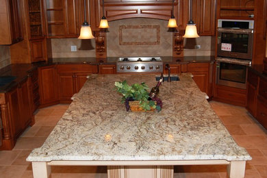 Enclosed kitchen - mid-sized u-shaped travertine floor enclosed kitchen idea in Chicago with granite countertops, raised-panel cabinets, medium tone wood cabinets, beige backsplash and an island