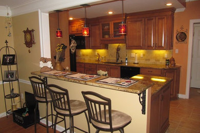 Eat-in kitchen - mid-sized traditional galley porcelain tile and beige floor eat-in kitchen idea in Other with a double-bowl sink, raised-panel cabinets, medium tone wood cabinets, granite countertops, beige backsplash, stone tile backsplash, black appliances and a peninsula