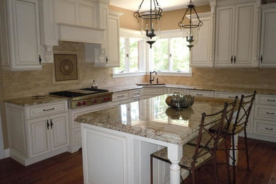 Enclosed kitchen - mid-sized transitional l-shaped medium tone wood floor enclosed kitchen idea in St Louis with a drop-in sink, recessed-panel cabinets, white cabinets, quartz countertops, beige backsplash, stainless steel appliances, an island and stone tile backsplash