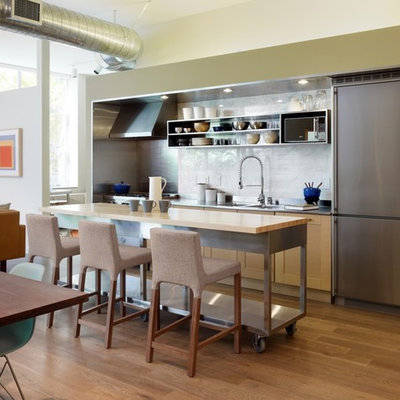 Urban single-wall open concept kitchen photo in Los Angeles with stainless steel countertops, open cabinets, an integrated sink, stainless steel cabinets, white backsplash, stone slab backsplash and stainless steel appliances
