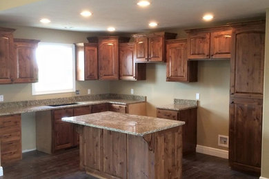 Kitchen photo in Other with medium tone wood cabinets, granite countertops and an island