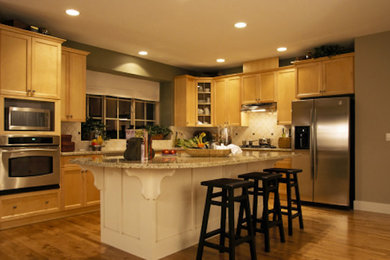 Exemple d'une cuisine chic en bois clair avec un plan de travail en granite, un électroménager en acier inoxydable, un sol en bois brun et îlot.