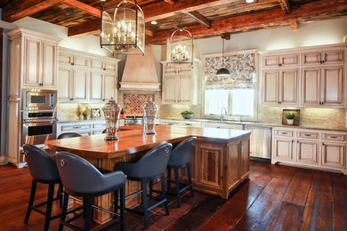 Inspiration for a mid-sized rustic l-shaped dark wood floor and brown floor eat-in kitchen remodel in New Orleans with an undermount sink, recessed-panel cabinets, distressed cabinets, wood countertops, beige backsplash, ceramic backsplash, stainless steel appliances and an island