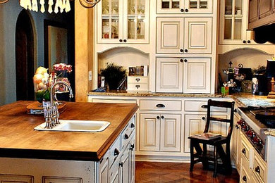 Example of a classic medium tone wood floor kitchen design in Other with a drop-in sink, distressed cabinets, granite countertops, stainless steel appliances and an island