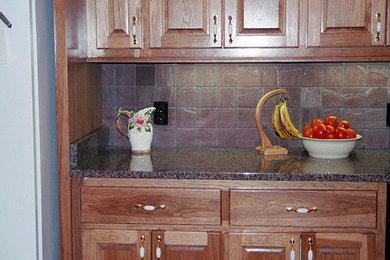 Example of a classic kitchen design in Atlanta with an undermount sink, raised-panel cabinets, medium tone wood cabinets, granite countertops, multicolored backsplash and terra-cotta backsplash
