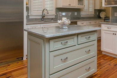Inspiration for a mid-sized u-shaped medium tone wood floor open concept kitchen remodel in Charleston with recessed-panel cabinets, blue cabinets, quartzite countertops, gray backsplash, ceramic backsplash, stainless steel appliances and an island