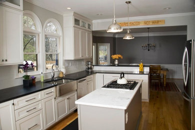 Inspiration for a timeless kitchen remodel in Atlanta with a farmhouse sink, flat-panel cabinets, white cabinets, granite countertops, white backsplash, stainless steel appliances and an island