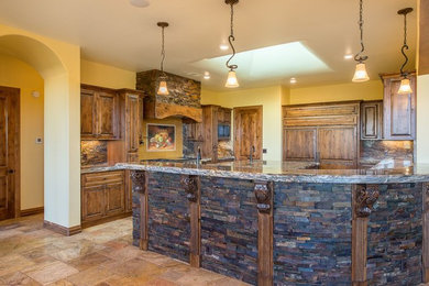Example of a large arts and crafts l-shaped ceramic tile and beige floor enclosed kitchen design in Albuquerque with medium tone wood cabinets, multicolored backsplash, stainless steel appliances, an island, raised-panel cabinets, granite countertops and stone slab backsplash