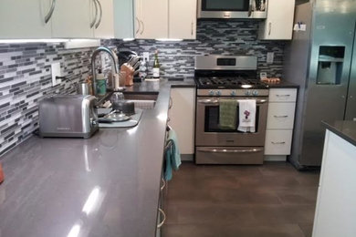 Example of a mid-sized trendy ceramic tile eat-in kitchen design in Other with a drop-in sink, flat-panel cabinets, white cabinets, multicolored backsplash, stainless steel appliances and an island
