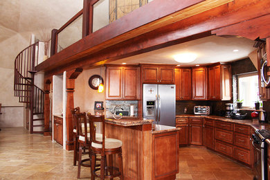 Example of a mid-sized mountain style u-shaped travertine floor eat-in kitchen design in Albuquerque with raised-panel cabinets, dark wood cabinets, granite countertops, multicolored backsplash, glass tile backsplash, stainless steel appliances and a peninsula