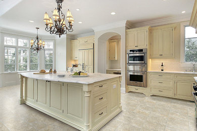 Large elegant l-shaped enclosed kitchen photo in Jackson with marble countertops, white backsplash, stainless steel appliances, an island, an undermount sink, raised-panel cabinets, beige cabinets and ceramic backsplash