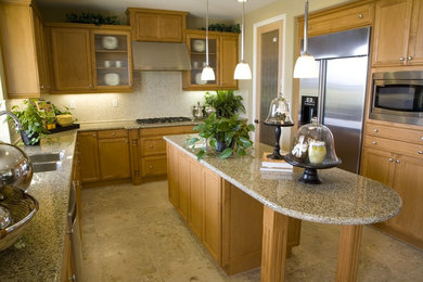 Modelo de cocina clásica renovada con fregadero encastrado, puertas de armario de madera clara, encimera de granito, electrodomésticos de acero inoxidable, una isla y salpicadero beige