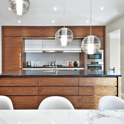 Inspiration for a modern galley eat-in kitchen remodel in Toronto with an undermount sink, flat-panel cabinets, dark wood cabinets, marble countertops, white backsplash and paneled appliances