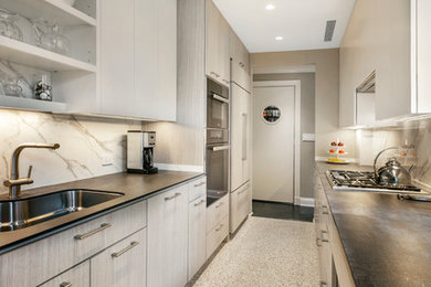 Large minimalist galley linoleum floor and multicolored floor enclosed kitchen photo in New York with an undermount sink, flat-panel cabinets, gray cabinets, soapstone countertops, white backsplash, stone slab backsplash, paneled appliances and no island