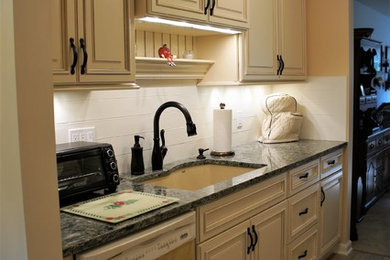 ブリッジポートにあるお手頃価格の小さなトラディショナルスタイルのおしゃれなキッチン (アンダーカウンターシンク、レイズドパネル扉のキャビネット、黄色いキャビネット、クオーツストーンカウンター、白いキッチンパネル、セラミックタイルのキッチンパネル、白い調理設備、セラミックタイルの床、ベージュの床) の写真