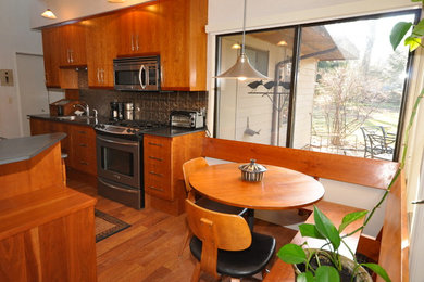 Eat-in kitchen - small 1960s galley medium tone wood floor eat-in kitchen idea in Grand Rapids with an undermount sink, flat-panel cabinets, medium tone wood cabinets, solid surface countertops, metal backsplash, stainless steel appliances and an island