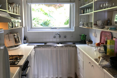 Photo of a small contemporary galley enclosed kitchen in Sydney with a double-bowl sink, open cabinets, white cabinets, laminate countertops, white splashback, mosaic tiled splashback, white appliances, porcelain flooring, no island, pink floors and white worktops.