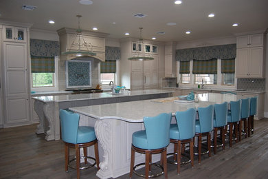 Open concept kitchen - huge transitional l-shaped painted wood floor and gray floor open concept kitchen idea in New Orleans with an undermount sink, beaded inset cabinets, white cabinets, marble countertops, gray backsplash, ceramic backsplash, stainless steel appliances and two islands