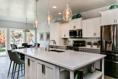 Example of a mid-sized transitional single-wall vinyl floor and gray floor eat-in kitchen design in Boise with a double-bowl sink, shaker cabinets, white cabinets, quartz countertops, gray backsplash, glass tile backsplash, stainless steel appliances, an island and white countertops