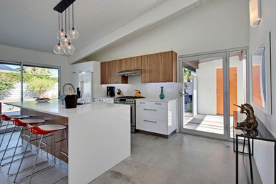 Open concept kitchen - mid-sized 1950s single-wall concrete floor open concept kitchen idea in Los Angeles with an undermount sink, flat-panel cabinets, white cabinets, quartz countertops, white backsplash, ceramic backsplash, stainless steel appliances and an island