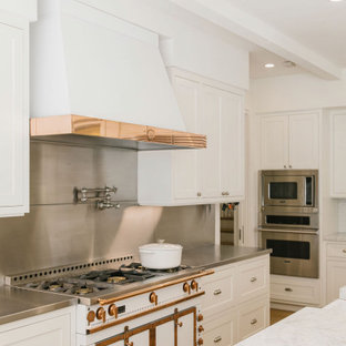Foto di una grande cucina country con lavello stile country, ante con riquadro incassato, ante bianche, top in marmo, paraspruzzi a effetto metallico, paraspruzzi in gres porcellanato, elettrodomestici bianchi, parquet chiaro, isola, pavimento marrone, top bianco e soffitto in legno