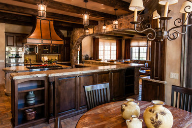 Modelo de cocina comedor rústica con puertas de armario de madera en tonos medios, electrodomésticos de acero inoxidable y una isla