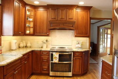 Enclosed kitchen - mid-sized traditional u-shaped light wood floor enclosed kitchen idea in Boston with an undermount sink, raised-panel cabinets, medium tone wood cabinets, beige backsplash, stainless steel appliances and no island