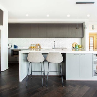 Contemporary l-shaped kitchen in Melbourne with an undermount sink, dark wood cabinets, quartz benchtops, white splashback, ceramic splashback, painted wood floors, with island, brown floor and white benchtop.
