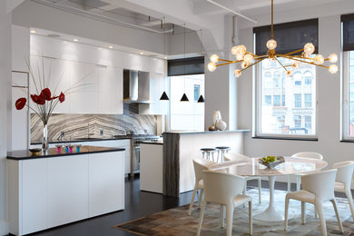 Photo of a medium sized modern l-shaped kitchen/diner in New York with a submerged sink, flat-panel cabinets, white cabinets, stone slab splashback, integrated appliances, dark hardwood flooring, a breakfast bar, brown floors, black worktops, engineered stone countertops and multi-coloured splashback.