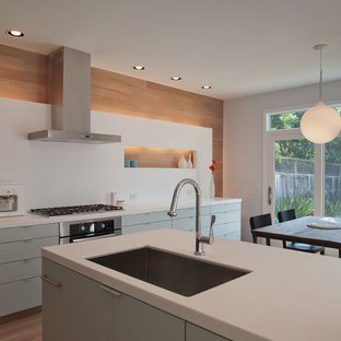 Cette photo montre une cuisine américaine moderne avec un évier 1 bac, un placard à porte plane, un plan de travail en quartz modifié, une crédence blanche, une crédence en dalle de pierre et des portes de placards vertess.