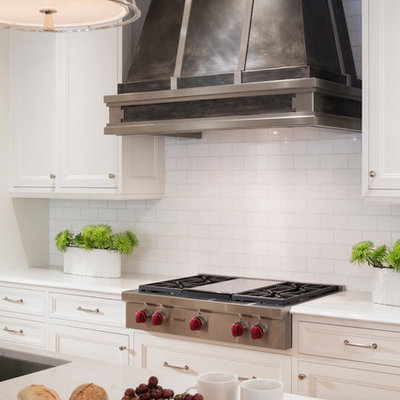 Inspiration for a large transitional l-shaped light wood floor eat-in kitchen remodel in Minneapolis with subway tile backsplash, paneled appliances, an island, a farmhouse sink, recessed-panel cabinets, white cabinets, quartzite countertops and white backsplash